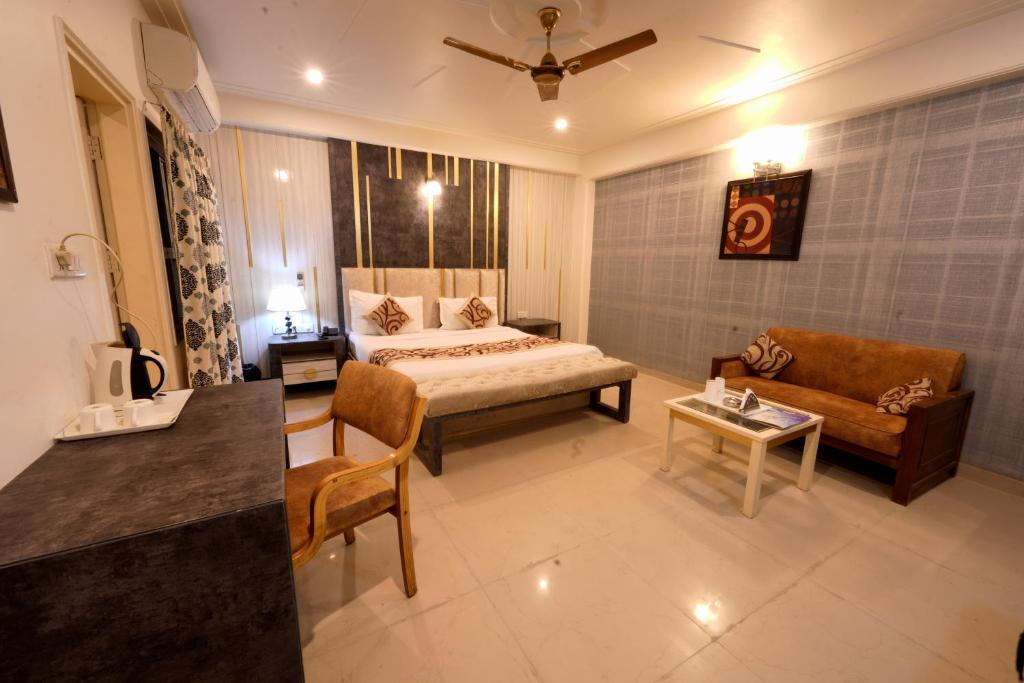 a bedroom with a bed and a couch and a table at Family Hotel Opera Near IGI Airport in New Delhi