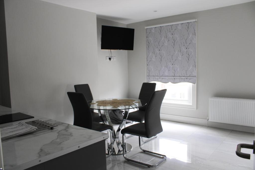 a dining room with a glass table and black chairs at MOXIE LUXURY APARTMENTS in Belfast