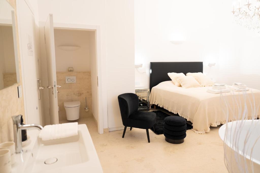 una camera bianca con un letto e una sedia nera di The White Knight Premium Boutique Hotel a Għajnsielem