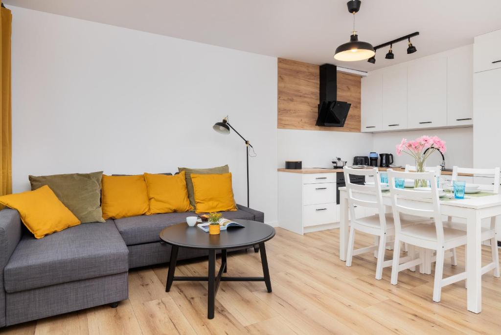 a living room with a couch and a table and a kitchen at Przystań Letnica Apartment with Balcony & Parking Gdańsk by Renters in Gdańsk