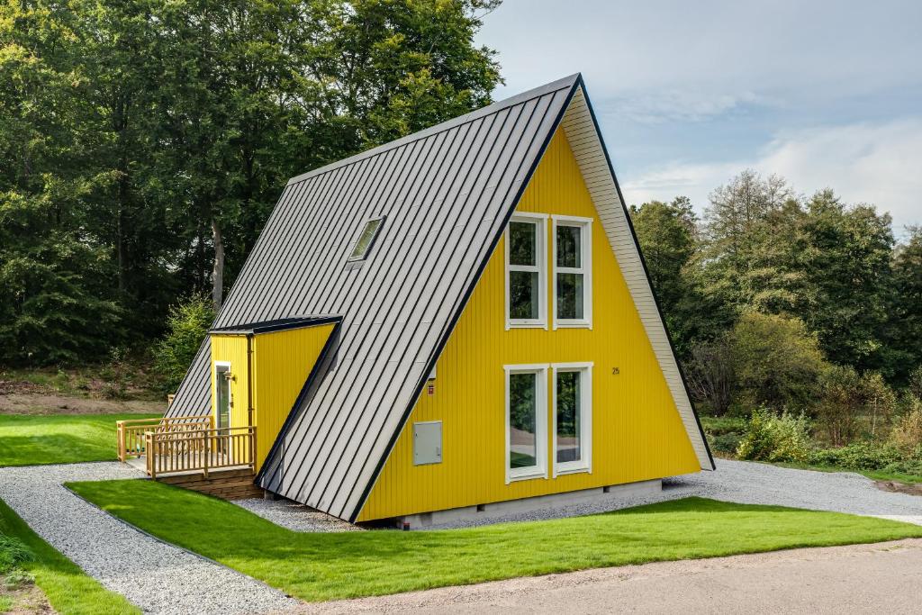 una pequeña casa amarilla con techo gris en Newly built westcoast dream home en Ängelholm