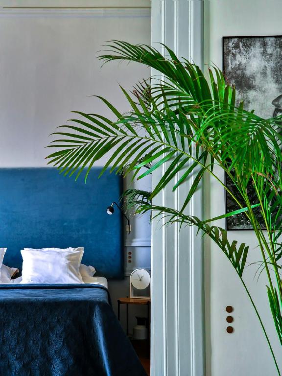 a bedroom with a blue bed and a green plant at Aristide Hotel - Small Luxury Hotels of the World in Ermoupoli