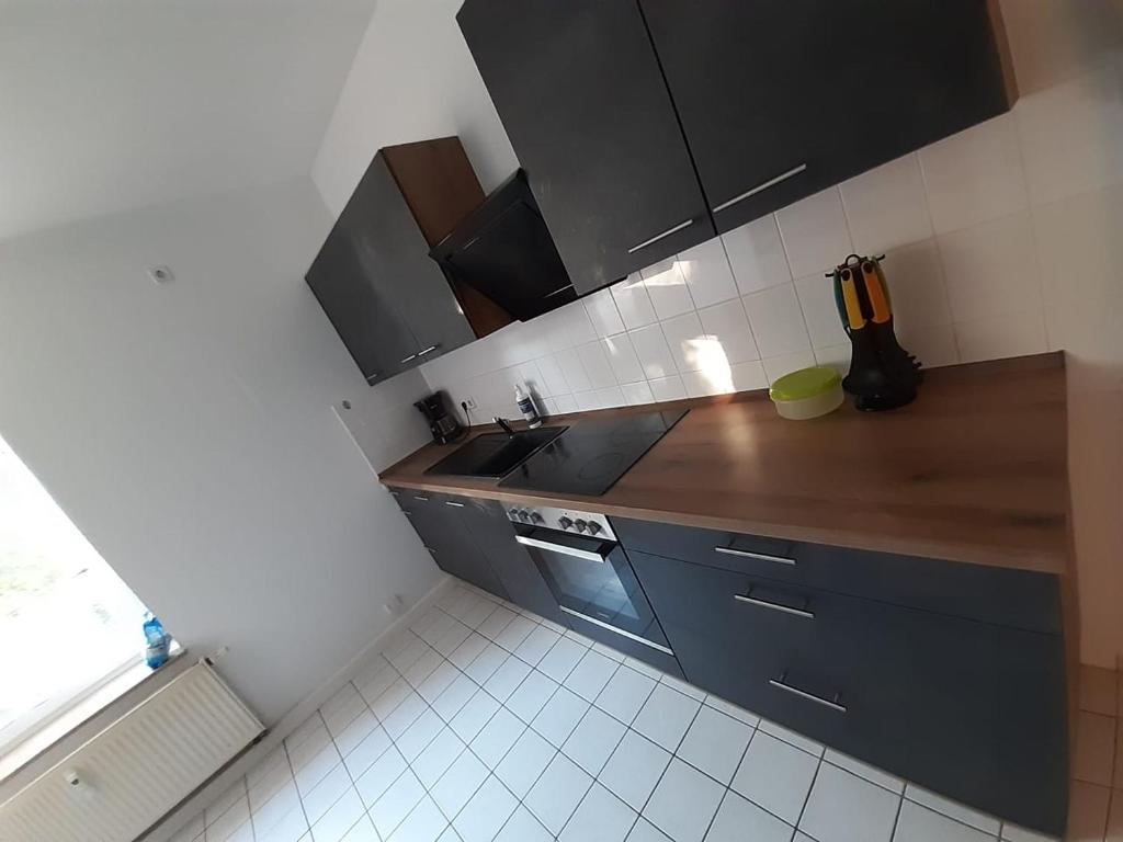 a kitchen with black cabinets and a wooden counter top at Mimalou möbliertes Apartment in Chemnitz in Chemnitz
