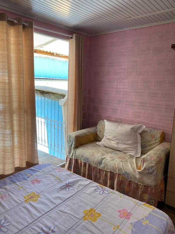 ein Schlafzimmer mit einem Bett, einem Sofa und einem Fenster in der Unterkunft Mini house Nara in Canela