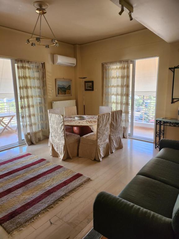 ein Wohnzimmer mit einem Tisch, Stühlen und einem Sofa in der Unterkunft Κεντρικό διαμέρισμα στη Γλυφάδα με θέα θάλασσα & ενοικίαση αυτοκινήτου in Athen