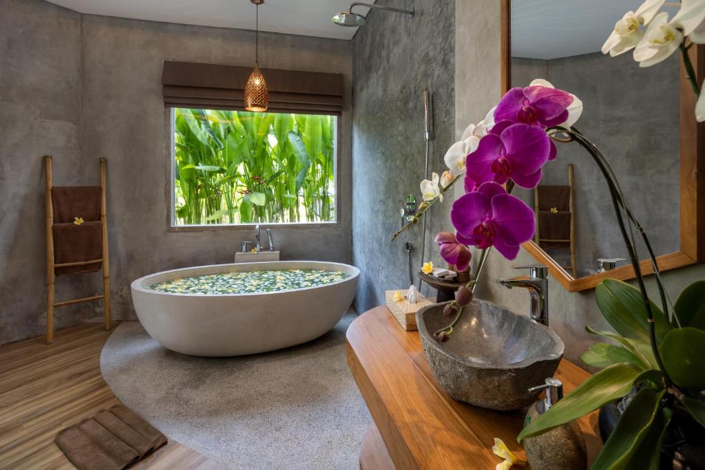 a bathroom with a large tub and a window at TheWakanda Resort A Pramana Experience in Ubud