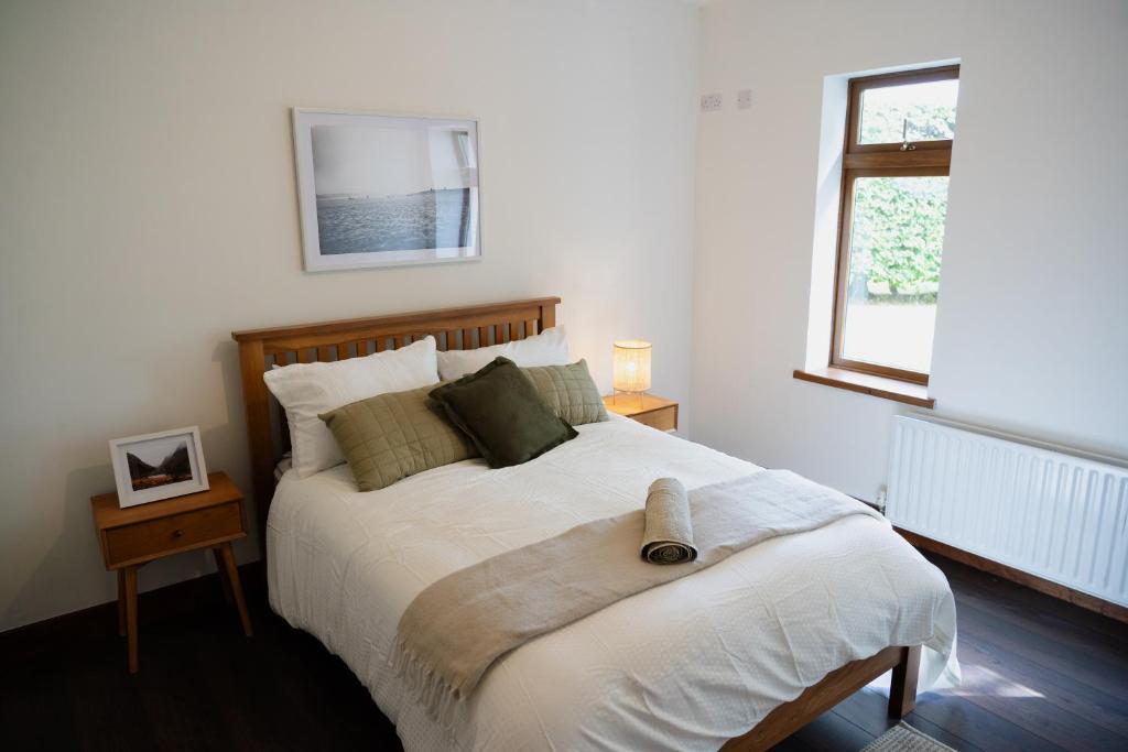 een slaapkamer met een groot bed met witte lakens en een raam bij Rossmore House in Monaghan