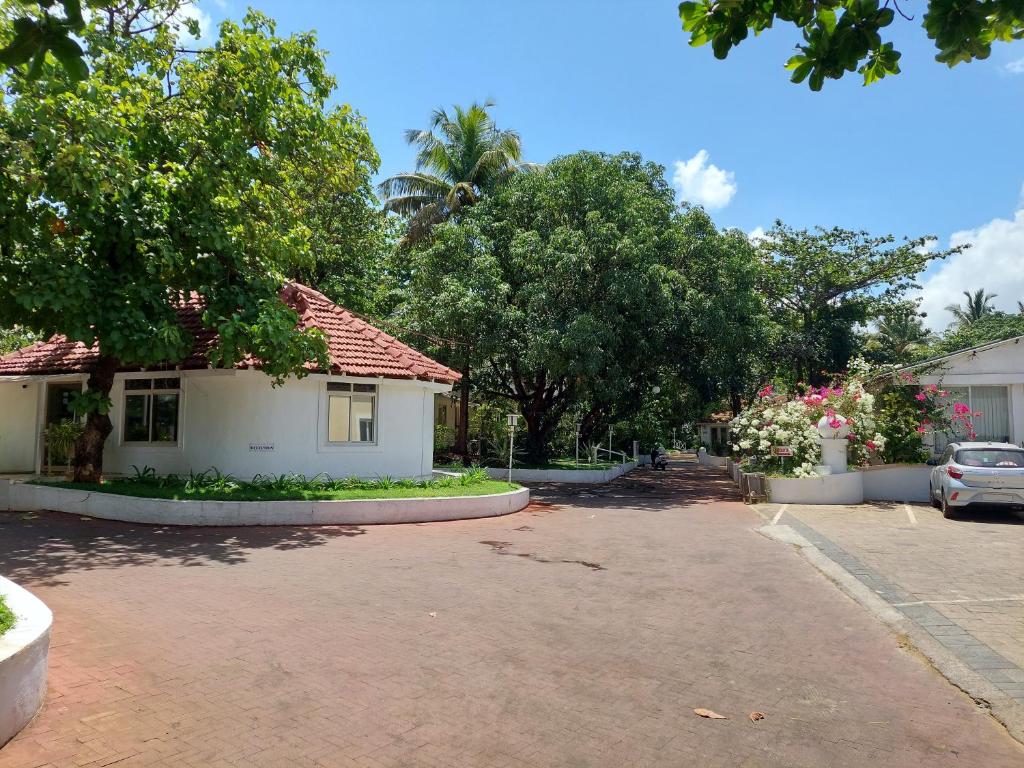 ein Haus in einer Straße mit Bäumen und einem Parkplatz in der Unterkunft Angels Resort in Porvorim