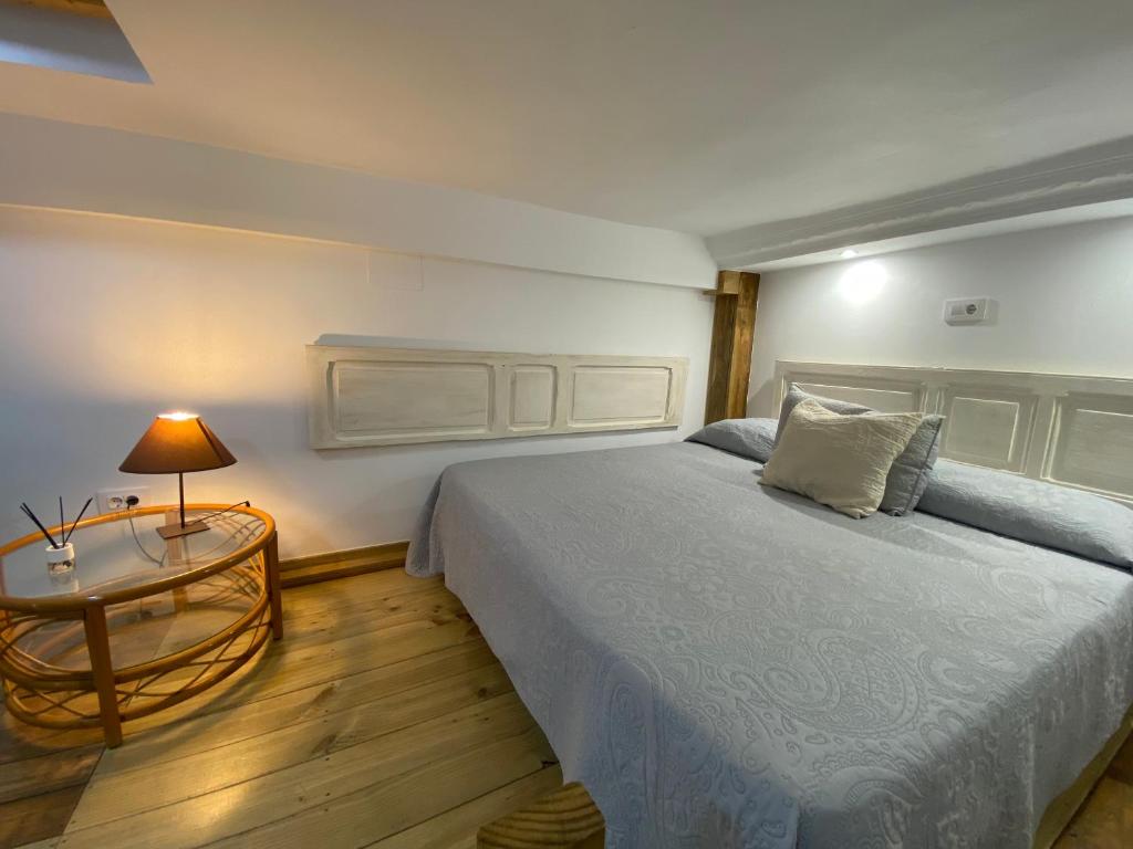 1 dormitorio con 1 cama y 1 mesa con lámpara en Vacacionales Vegueta, en Las Palmas de Gran Canaria