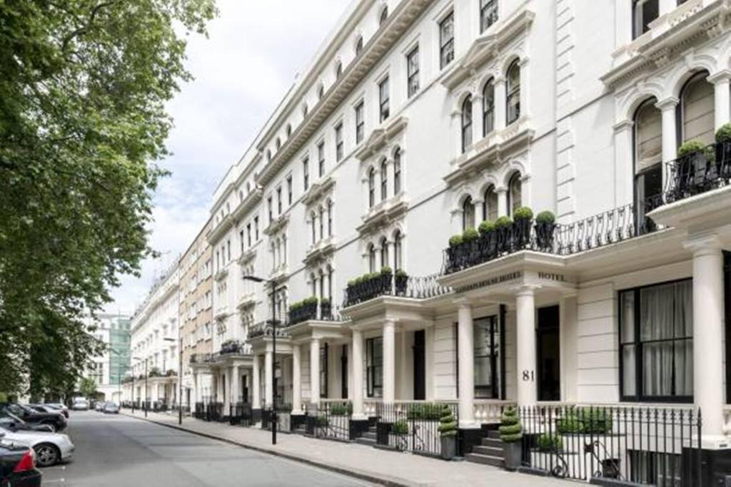 a large white building with potted plants on a street at London House Hotel in London