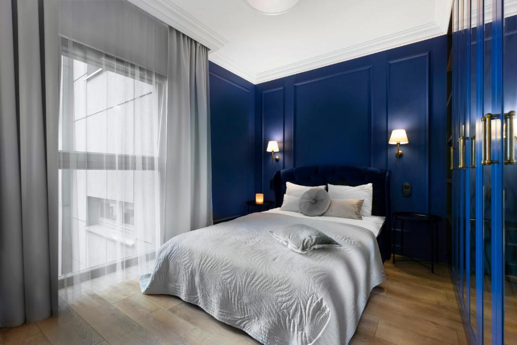 Elite Apartments Grano Residence في غدانسك: غرفة نوم زرقاء مع سرير ونافذة