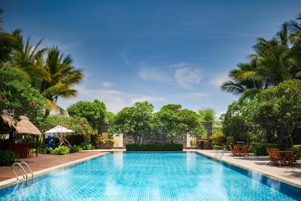 a pool at a resort with palm trees at eL Hotel Banyuwangi in Banyuwangi