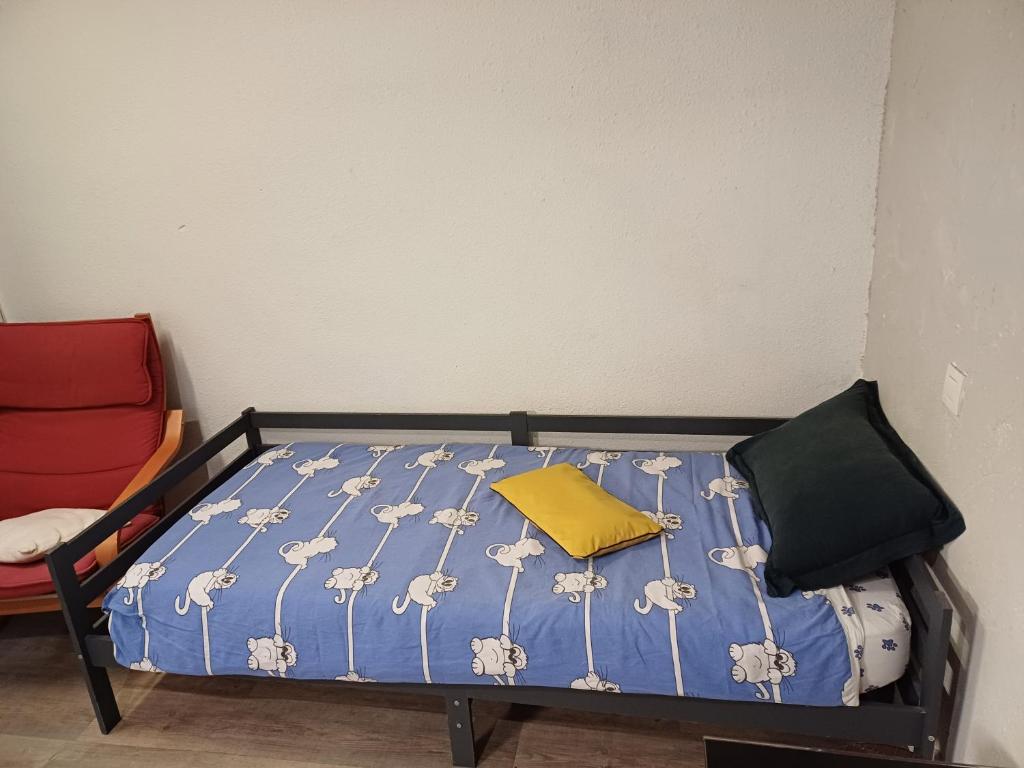 a bed with a yellow pillow and a red chair at Studio Perpignan in Perpignan