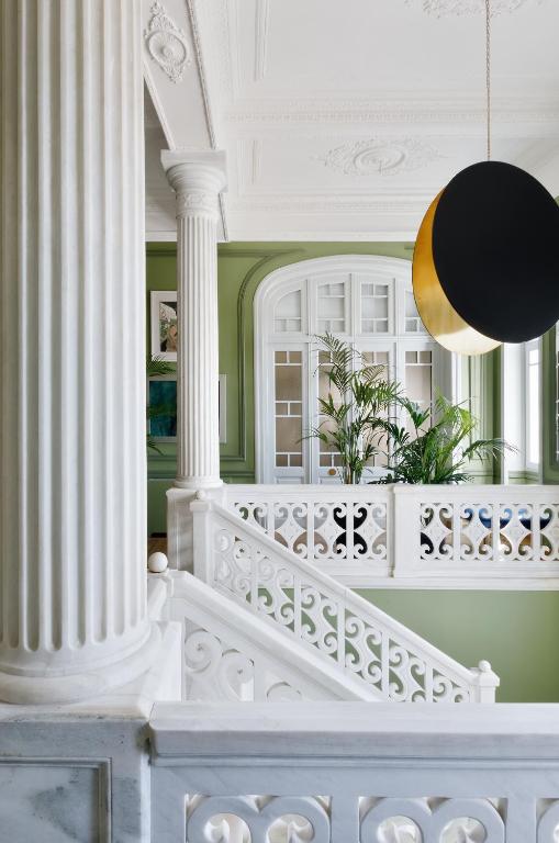 a staircase with white columns and a pendant light at Aristide Hotel - Small Luxury Hotels of the World in Ermoupoli