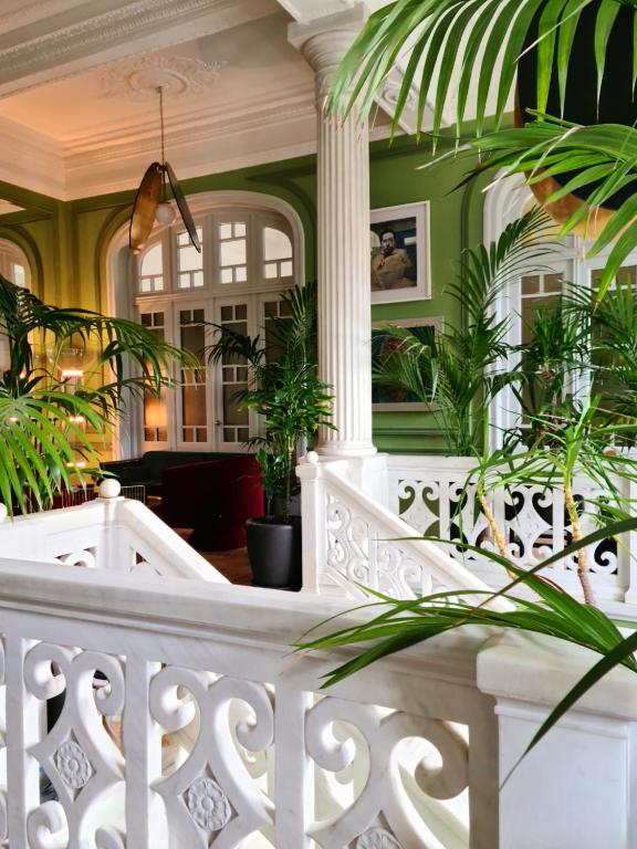 a white staircase with plants in a lobby at Aristide Hotel - Small Luxury Hotels of the World in Ermoupoli