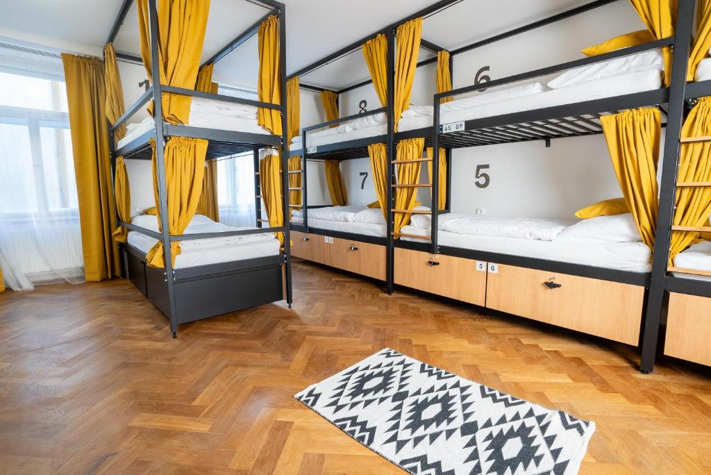 White Wolf House Hostel & Apartments في براغ: غرفة بها أربعة أسرة بطابقين وأرضية خشبية