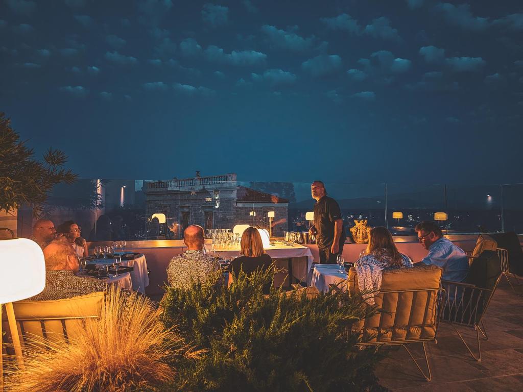a group of people sitting at tables on a patio at Aristide Hotel - Small Luxury Hotels of the World in Ermoupoli