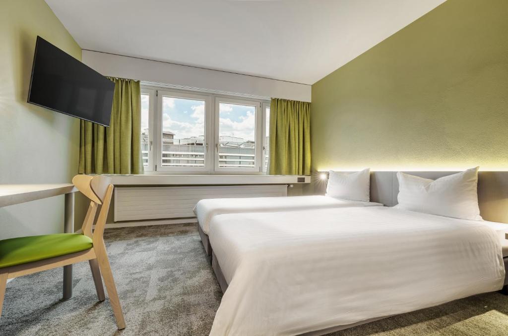 ein Hotelzimmer mit einem Bett, einem Schreibtisch und einem Fenster in der Unterkunft flexymotel Wil in Wil