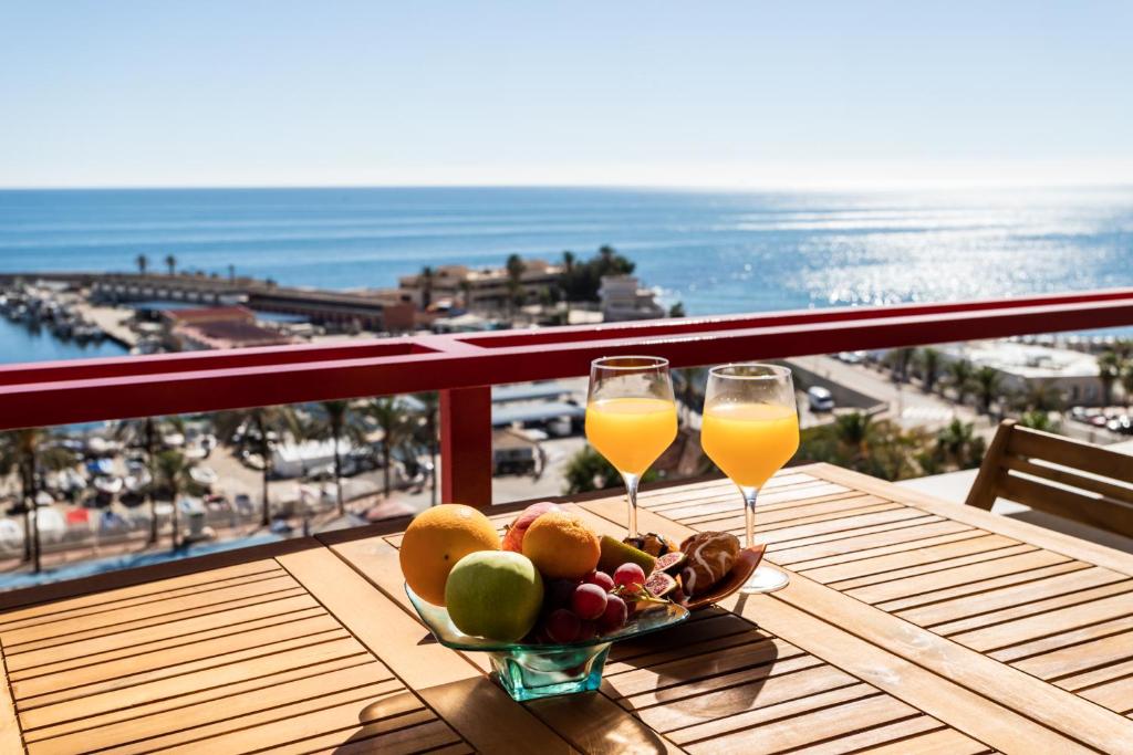 una mesa con dos vasos de zumo de naranja y un bol de fruta en Sur Suites Palmeras 11, en Fuengirola