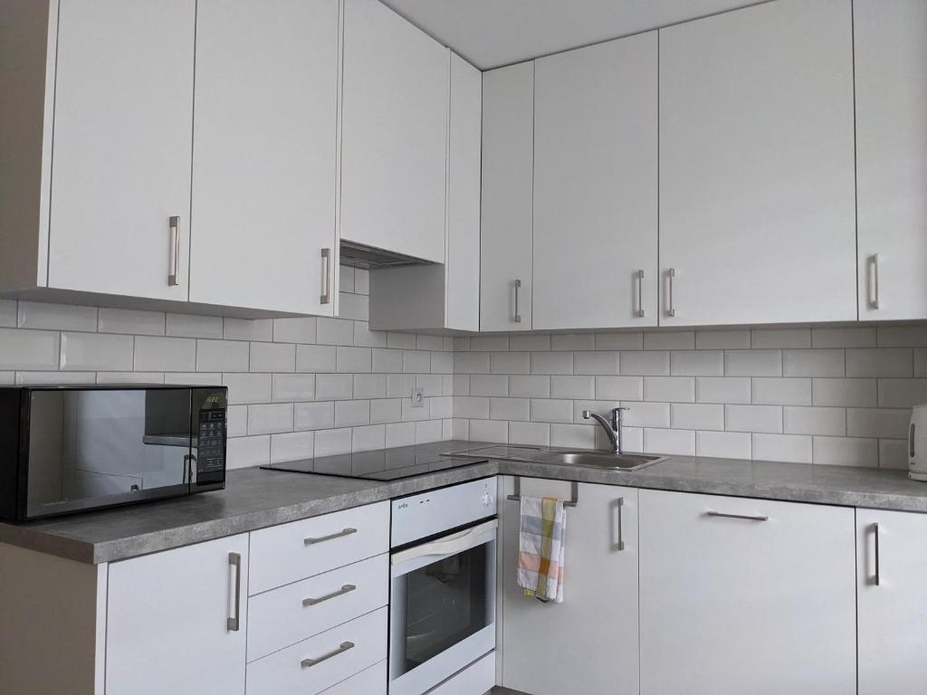 eine weiße Küche mit weißen Schränken und einer Mikrowelle in der Unterkunft Rigel Rooms in Piotrków Trybunalski