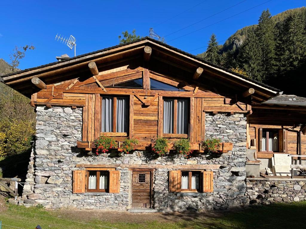 una baita di tronchi con fiori alle finestre di Bed and Breakfast Campo Base a Carona