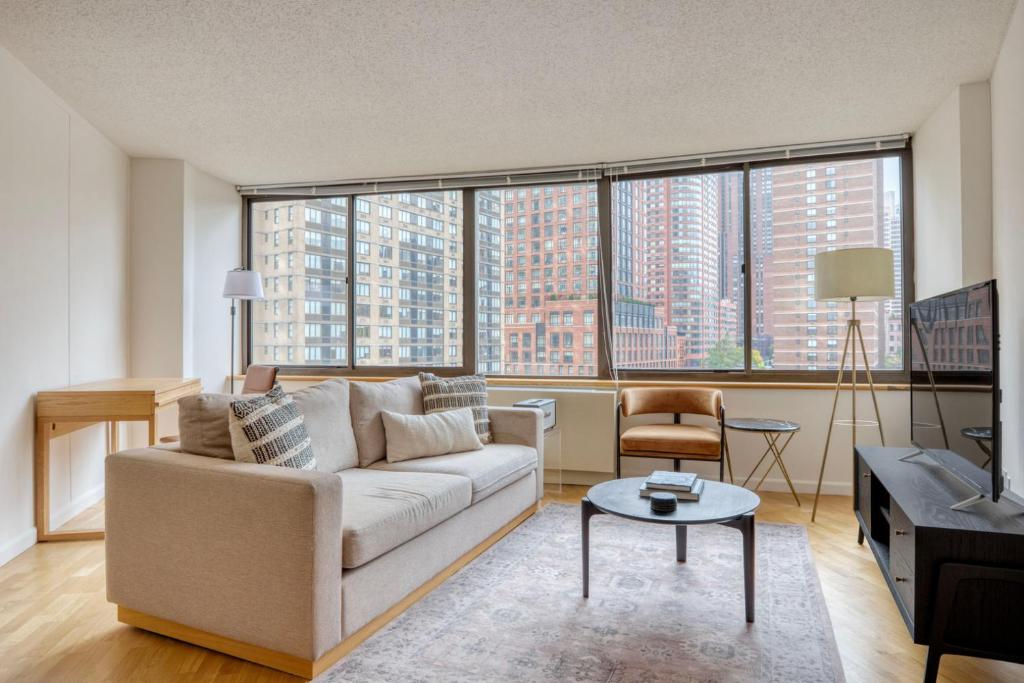 sala de estar con sofá y ventanas grandes en UES 2br w doorman gym nr central park NYC-1299, en Nueva York