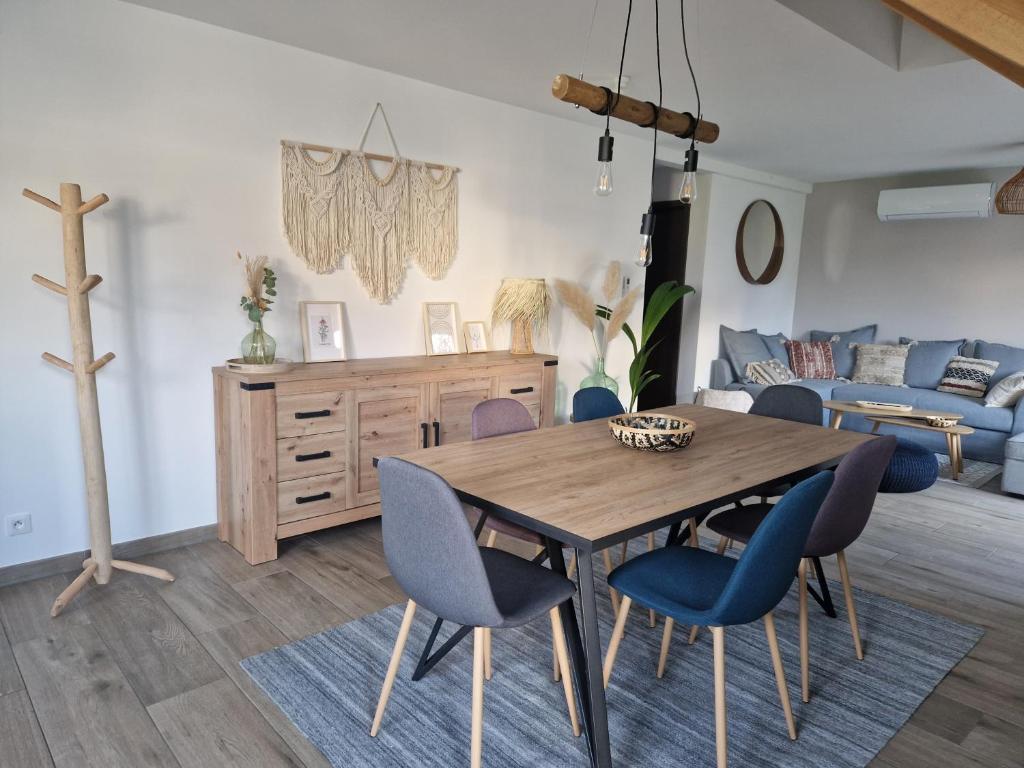 ein Wohnzimmer mit einem Holztisch und blauen Stühlen in der Unterkunft Chez Iris in Jebsheim