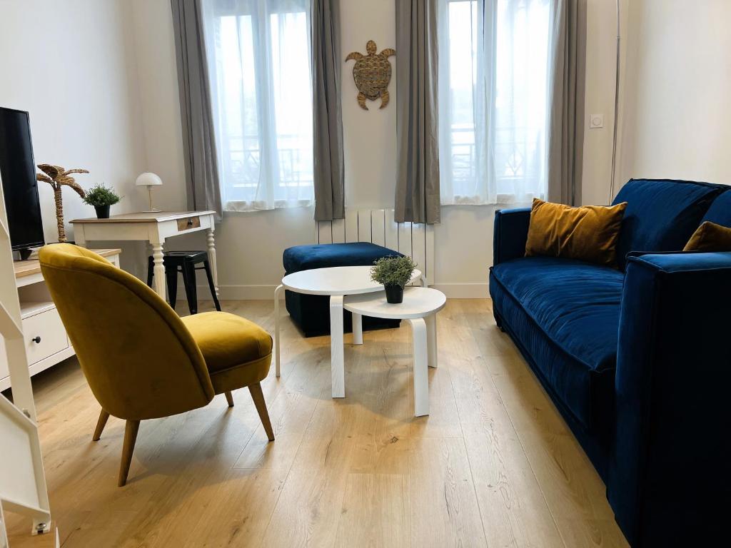 een woonkamer met een blauwe bank en een tafel bij Villa Saint Jacques , Duplex Les Galets in Le Tréport