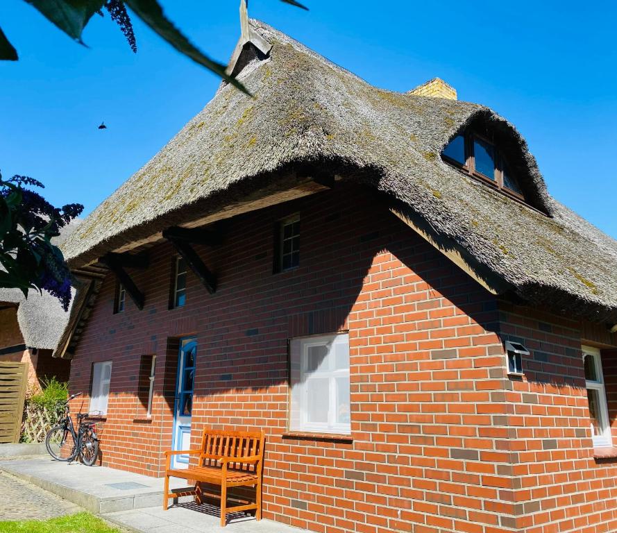 ein Gebäude mit einem Strohdach und einer Bank davor in der Unterkunft Ferienwohnung unter dem Reetdach in Wustrow