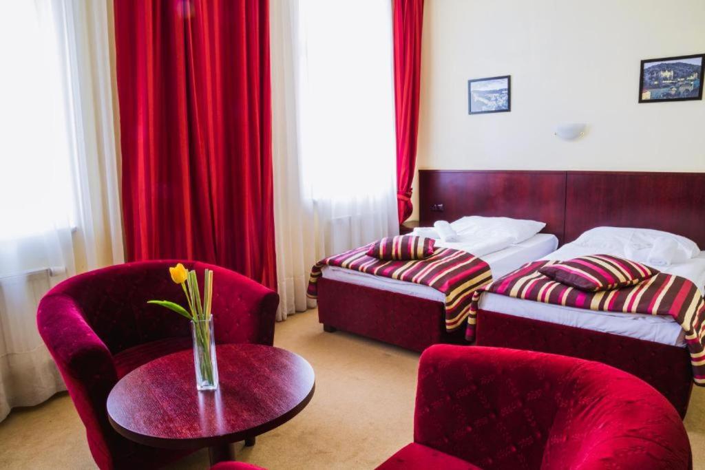 um quarto de hotel com duas camas e uma mesa e cadeiras em Hotel Adria em Karlovy Vary