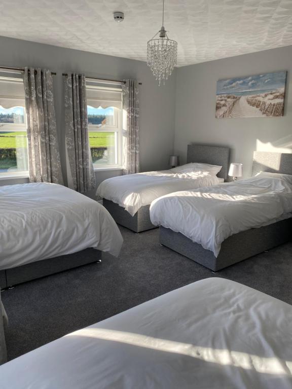 a bedroom with three beds and a chandelier at New Lisnagalt Lodge in Coleraine