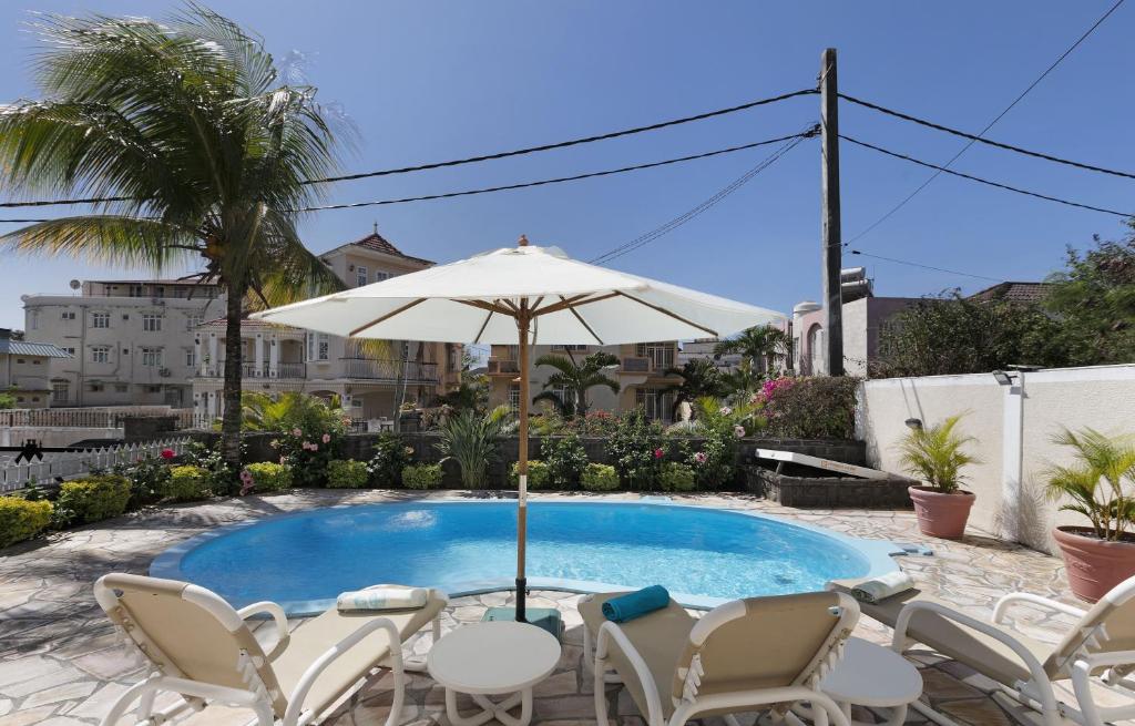 a patio with chairs and an umbrella and a pool at Apartment Hibiscus in Grand-Baie