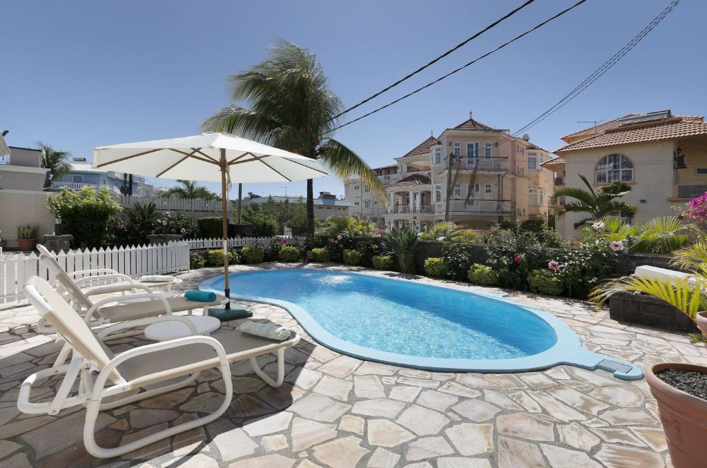 a swimming pool with two chairs and an umbrella at Apartment Orchid in Mont Choisy