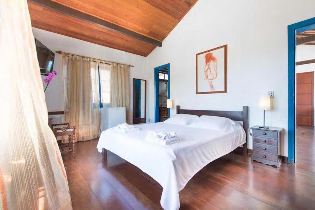 1 dormitorio con 1 cama blanca grande y suelo de madera en Casa do canto, en Búzios