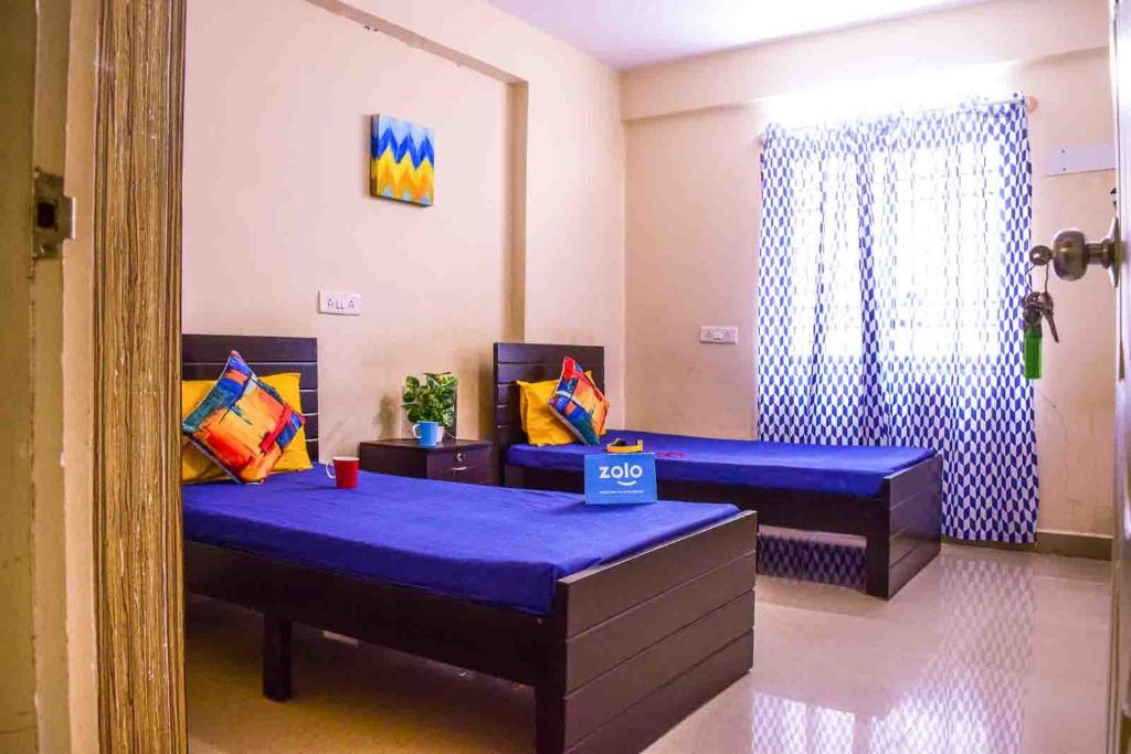 een kamer met 2 bedden met paarse lakens en een raam bij Nallur Mylooran Arangam in Jaffna