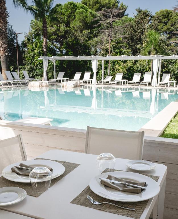 a white table with chairs and a swimming pool at San Lorenzo Boutique Hotel & SPA in Polignano a Mare
