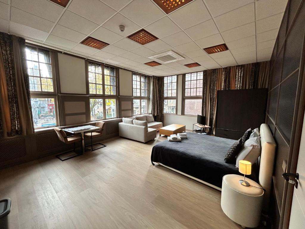 a bedroom with a bed and a living room with windows at Stylish Studio S1, City Centre Dordrecht in Dordrecht