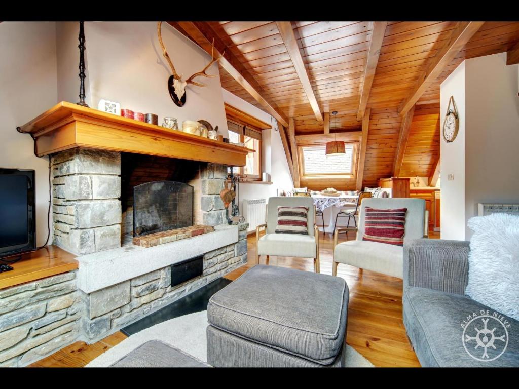 a living room with a stone fireplace and a tv at CASA REINA de Alma de Nieve in Tredós