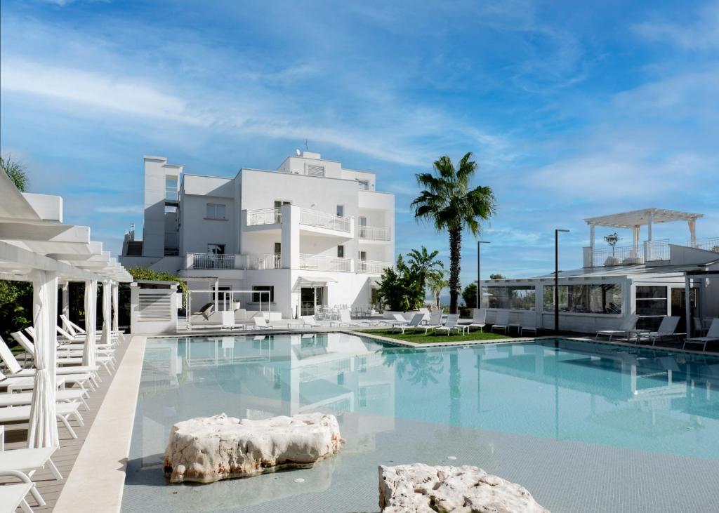 une grande piscine en face d'un bâtiment blanc dans l'établissement San Lorenzo Boutique Hotel & SPA, à Polignano a Mare
