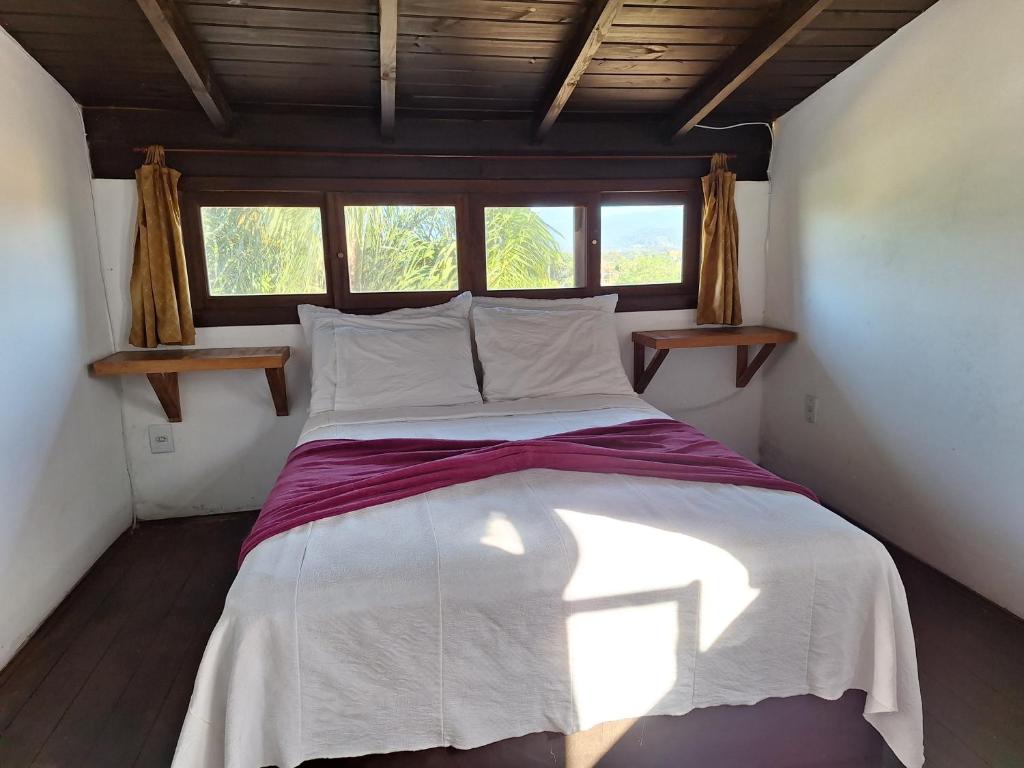 een groot bed in een kamer met een raam bij Hospedaria Noite Lunar in Praia do Rosa