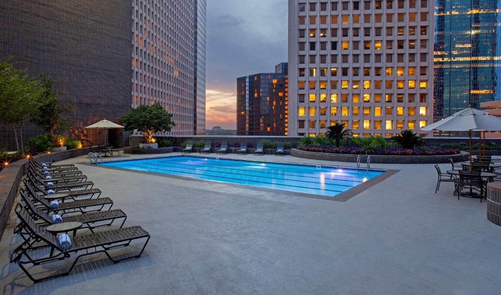 uma piscina com cadeiras, mesas e edifícios em Hyatt Regency Houston em Houston