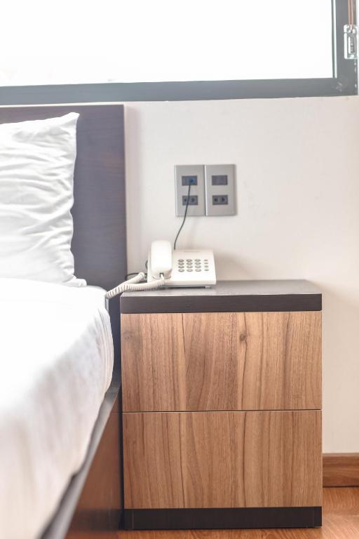 a bedroom with a bed and a phone on a night stand at TTR Midtown View Hotel in Da Lat