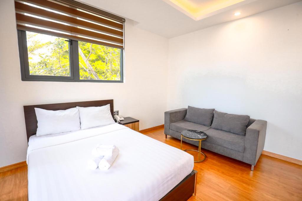 a bedroom with a bed and a couch at TTR Midtown View Hotel in Da Lat