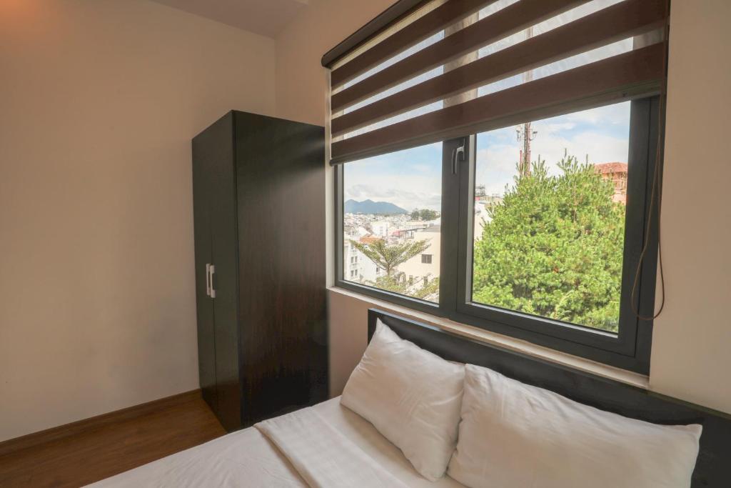 a bedroom with a bed and a large window at TTR Midtown View Hotel in Da Lat
