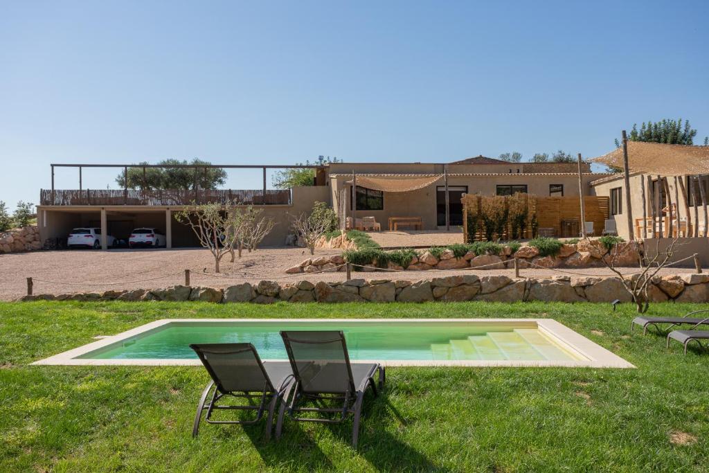 a yard with two chairs and a swimming pool at Casa de campo Masos de Pals con parking y piscina in Pals