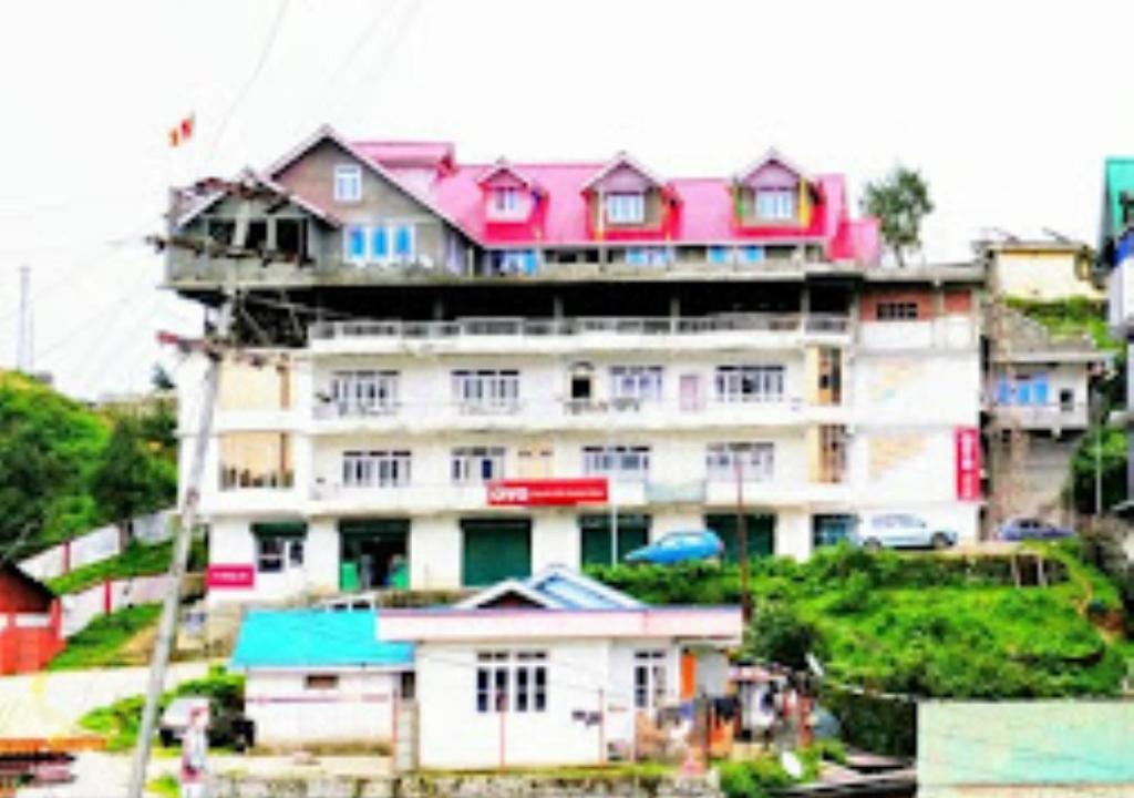 um grande edifício com telhados cor-de-rosa em cima em Hotel North Hill Arunachal Pradesh em Tawang