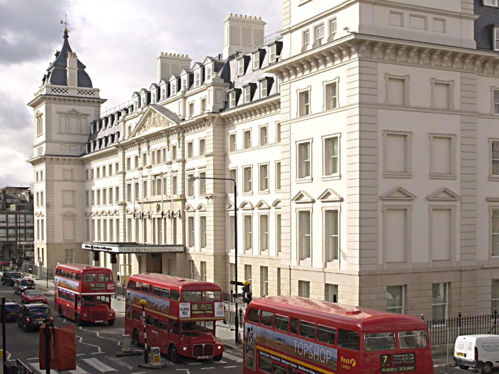 two red double decker buses on a city street at Hilton London Paddington in London