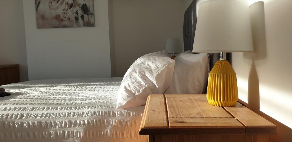 Una cama con una mesa con una lámpara. en Comfort Stay Rooms, en Portslade-by-Sea