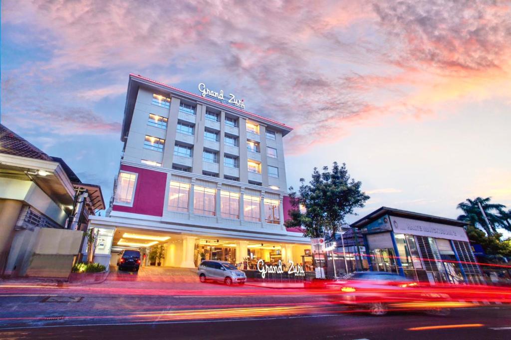 a building on a city street with cars driving past it at Grand Zuri Malioboro in Yogyakarta
