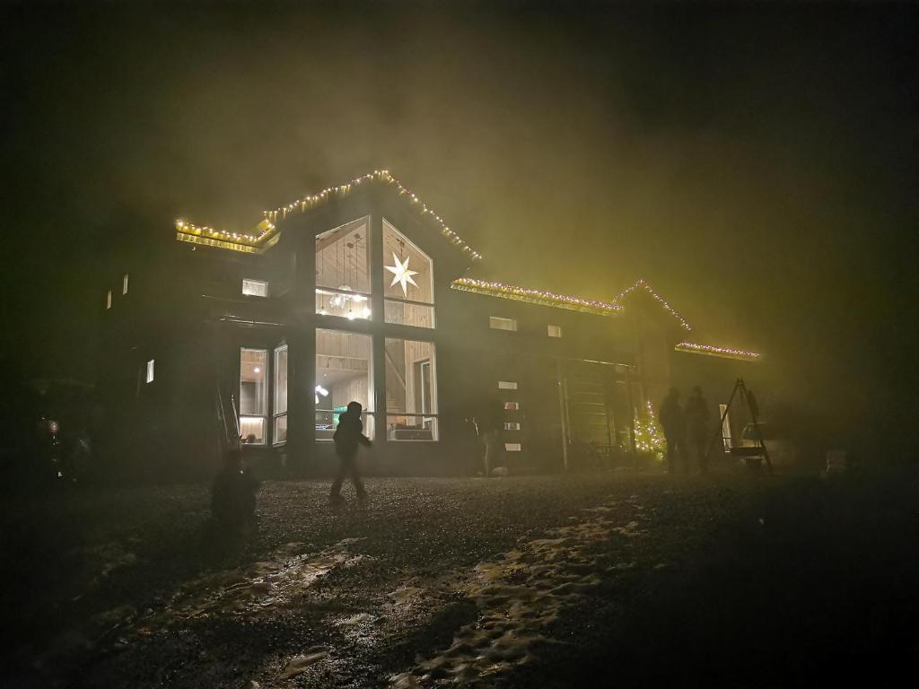 a person walking in front of a house with christmas lights at Moderne hytte i Svandalen, Sauda - nær skisenter og natur in Sauda